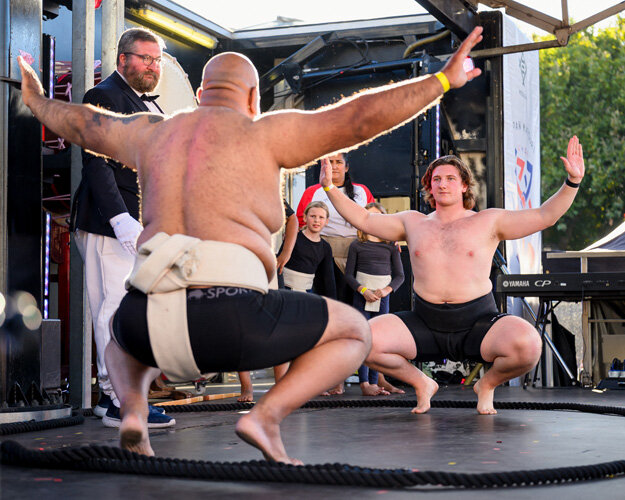 Two sumo wrestlers in the crouched starting position on an outdoor mat at Japan Matsuri in Trafalgar Square, London.